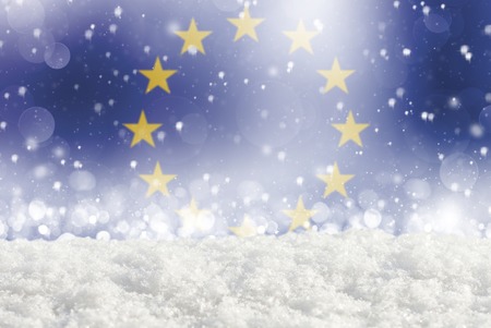 Defocused European union flag as a winter Christmas background with falling snow, snowdrift and bokehの写真素材