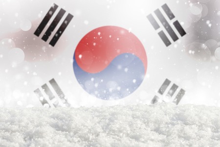 Defocused South Korea flag as a winter Christmas background with falling snow, snowdrift and bokehの写真素材