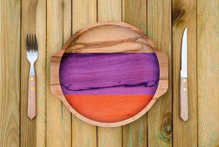 Concept of Russian cuisine. Wooden plate with a Russia flag, fork and knife on a wooden backgroundの写真素材