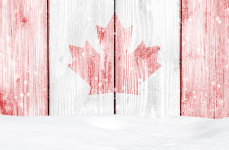 Canada flag as Christmas background with white wooden wall, falling snow and snowdriftの写真素材