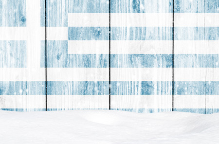 Greece flag as Christmas background with white wooden wall, falling snow and snowdriftの写真素材