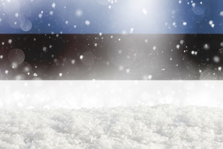 Defocused Estonia flag as a winter Christmas background with falling snow, snowdrift and bokehの写真素材