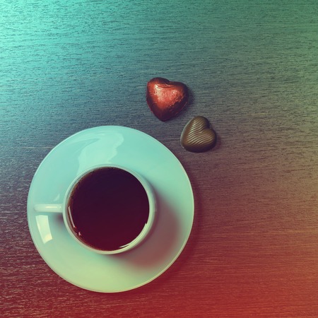 Background with cup of coffee and chocolate candy on dark. Photo in vintage styleの写真素材