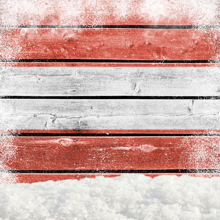 Winter background with wooden wall, falling snow, snowdrift and Austrian flagの写真素材