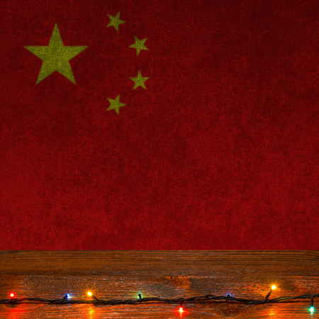 Festive grunge background with Christmas lights on a wooden surface and Chinese flagの写真素材