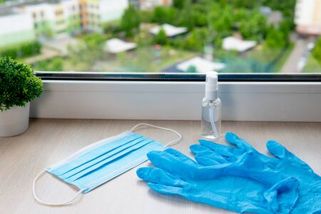 Blue medical gloves, mask and antiseptic gel on the windowsillの写真素材