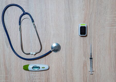 Doctor's equipment-stethoscope, thermometer, oximeter and syringe on wooden backgroundの写真素材