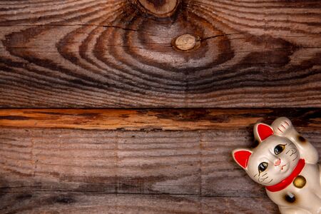 Japanese symbol of good luck Maneki Neko cat on old wooden background. Top viewの写真素材