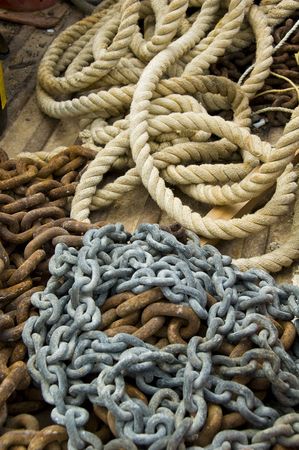 Pile of rusty chains and old rope on a wooden boat floor