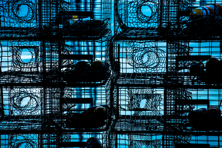 lobster traps stacked silhouetted against blue waterの写真素材