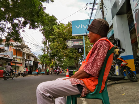 Probolinggo,Indonesia : dec. 2022 :an old man was sitting in a plastic chair looking out at the streetのeditorial素材