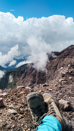 woman's feet wearing mountain boots with a background of mountain rocks and sea of clouds
