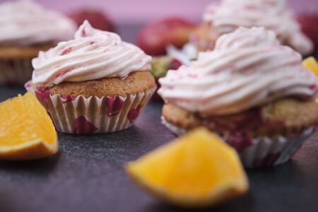 Orange cupcakes with strawberry filling and butter cream with fresh berries. Desserts on a dark background.の写真素材