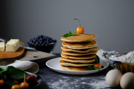 One-on-one pancakes cooked for breakfast. On the table are products from which the dish was prepared and berries.の写真素材