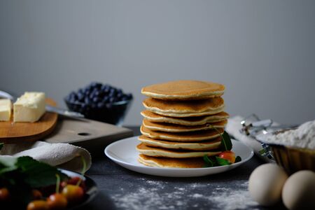 One-on-one pancakes cooked for breakfast. On the table are products from which the dish was prepared and berries.の写真素材