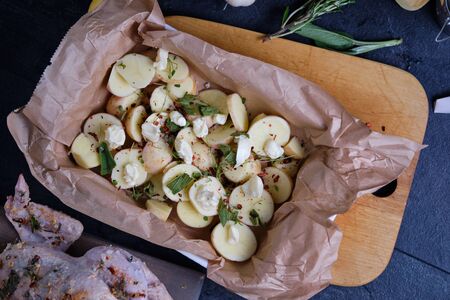 Cushion of potatoes for chicken. The process of cooking chicken with herbs, spices and lemon in the oven. On the table are the products that are needed for cooking. The hands of the cook in the frame.の写真素材