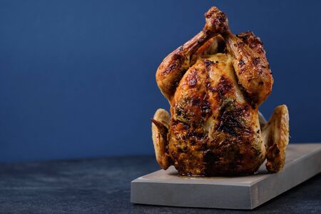 Oven baked chicken with spices, herbs and lemon on a wooden board with a beautiful golden brown crust.の写真素材