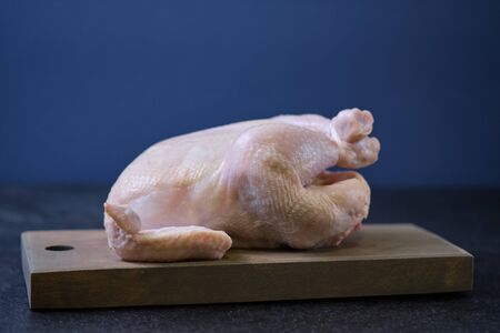 Chicken prepared for cooking on a wooden board.の写真素材