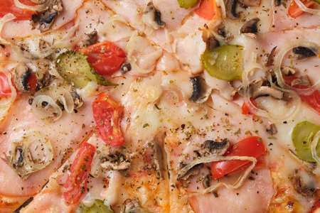 Pizza with tomatoes, cucumber, ham, mushrooms, onions, cheese and spices. A closeup of a pizza.の写真素材