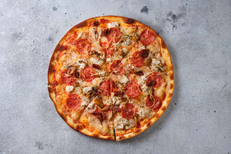 Pizza with sun-dried tomatoes, spicy sausage, chicken, onions, honey mushrooms, mozzarella cheese, spices and tomato sauce. Flat lay. On a light backgroundの写真素材