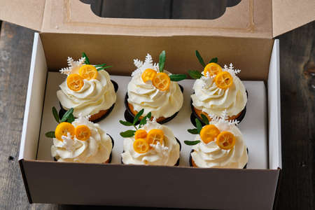 Festive muffins with cream cheese cream and citrus filling. Confectionery for the holiday. Dessert decorated with kumquat and tangerine, packed in a gift box.の写真素材