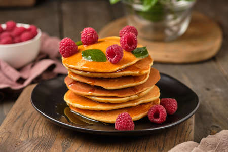 Flavored pancakes with honey and fresh raspberries for breakfast. Great breakfast dessert, garnished...