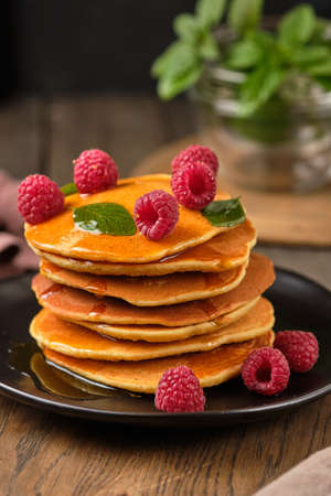 Flavored pancakes with honey and fresh raspberries for breakfast. Great breakfast dessert, garnished with fresh mint leaves.の写真素材