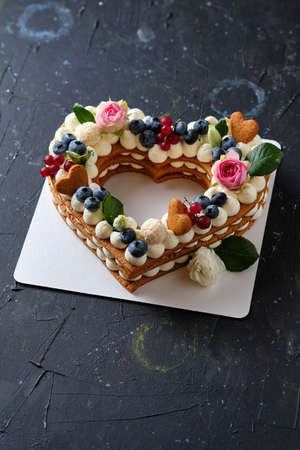 Honey cake with fresh blueberries, herbs and cream cheese cream. Dessert for a loved one. Heart cake.の写真素材