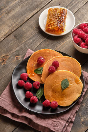 Flavored pancakes with honey and fresh raspberries for breakfast. Great breakfast dessert, garnished...