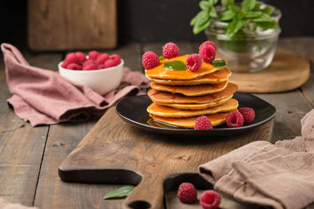 Flavored pancakes with honey and fresh raspberries for breakfast. Great breakfast dessert, garnished with fresh mint leaves.の写真素材