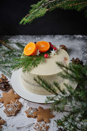Delicious New Year's cake with poppy sponge cake and tangerine filling. A beautiful holiday cake for Christmas decorated with tangerines, fresh berries, snowflakes and spruce twigs.の写真素材