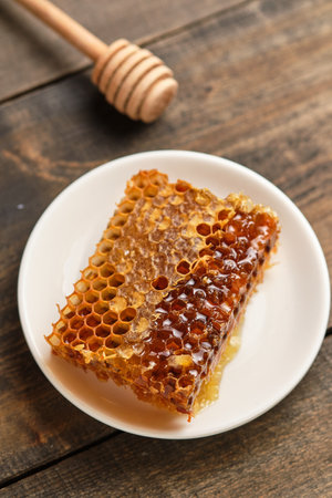 Honeycomb close-up. Fresh honey from the field and honey stick on an old wooden table.の写真素材
