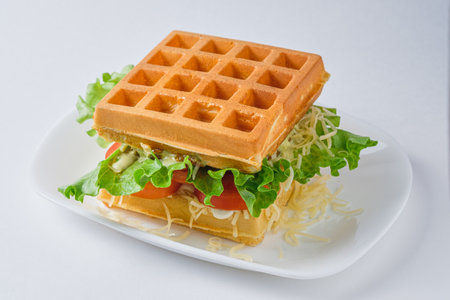 Belgian waffle sandwich with chicken, lettuce, tomato, cheese and mayonnaise. Dish on a white plate.の写真素材