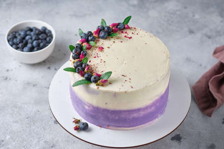 Delicious and beautiful handmade cake. Confectionery products for the holiday, to order. The dessert is decorated with fresh berries, green leaves and dried flowers.の写真素材