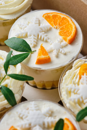 Holiday trifles with cream cheese cream and citrus filling. Confectionery for the holiday. Dessert decorated with kumquat, tangerine and green pistachio leaves, packed in a gift box.の写真素材