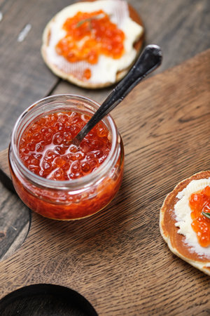 Pancakes with red caviar on a wooden table in a rustic style.の写真素材