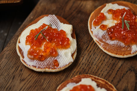 Pancakes with red caviar on a wooden table in a rustic style.の写真素材