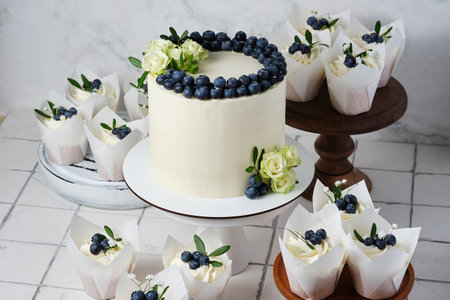 Wedding preparations. White wedding cake and cupcakes in the same style, decorated with fresh...