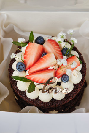 Chocolate bento cake decorated with strawberries, blueberries and flowers.の写真素材