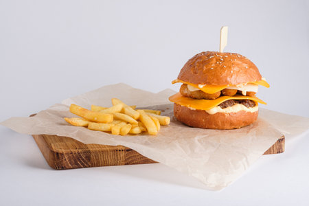 Cheese burger with 4 types of cheese and beef patty and french fries on wooden board on white background.の写真素材