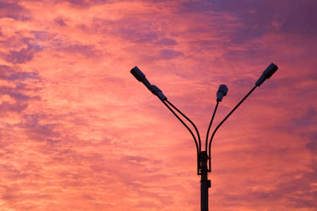 the threatening flame-colored sunset and silhouette of lamppostの写真素材