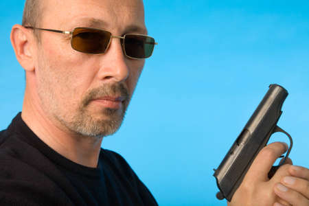 the mature man with gun on blue backgroundの写真素材