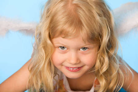 small girl dreessed as angel on blue backgroundの写真素材