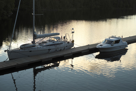 Island ÐÐ°Ð»Ð»Ð°Ð¼, the Monastery Bay  The sunset  The wooden pier moored sailing yacht and a small motor boat の写真素材