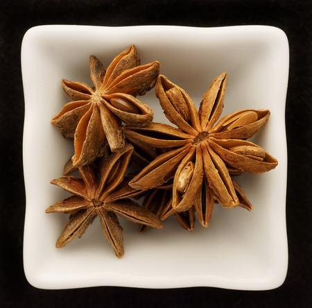 Spice star anise in a ceramic bowl. Isolated on black.の写真素材