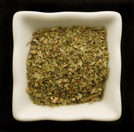 Spice oregano in a ceramic bowl. Isolated on black.の写真素材
