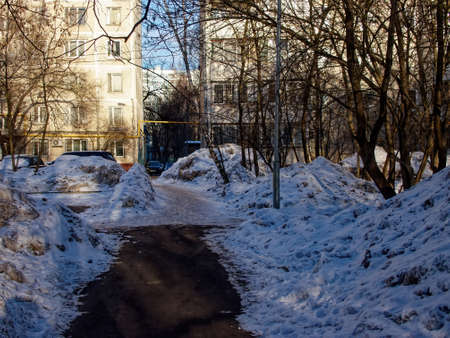 Asphalt path in the courtyard of the house, in winterの写真素材