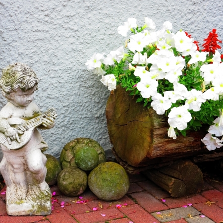 Garden arrangement with white petunia and a small sculptureの写真素材