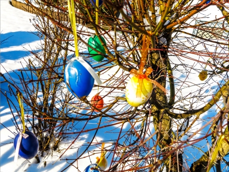 Colorful Easter eggs on tree in a snowy garden