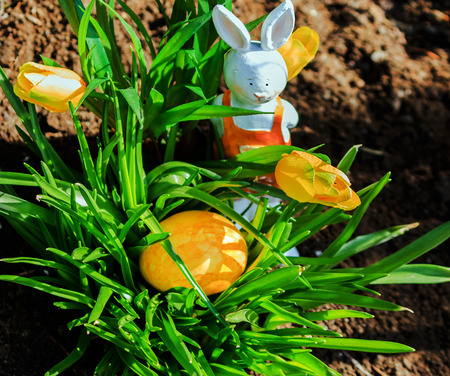 Yellow Easter egg and tulips in a garden